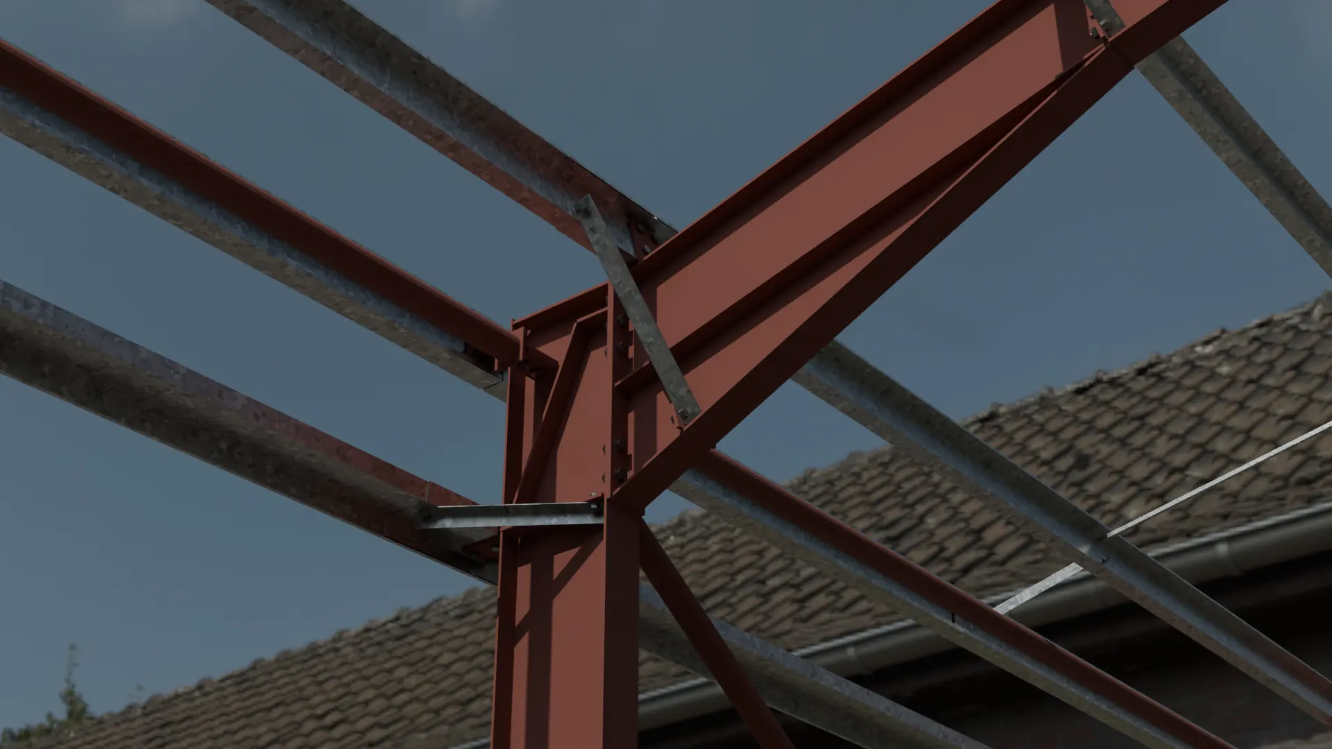 Red-oxide primed portal frame haunch with galvanised purlins against a grey sky